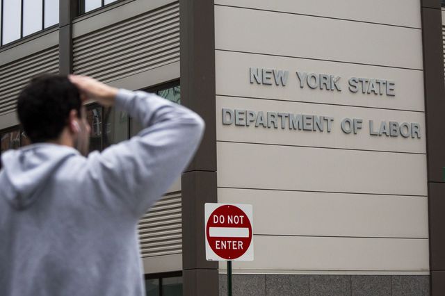 A pedestrian stands in front of the New York State Department of Labor office in Brooklyn on May 8th, 2020.